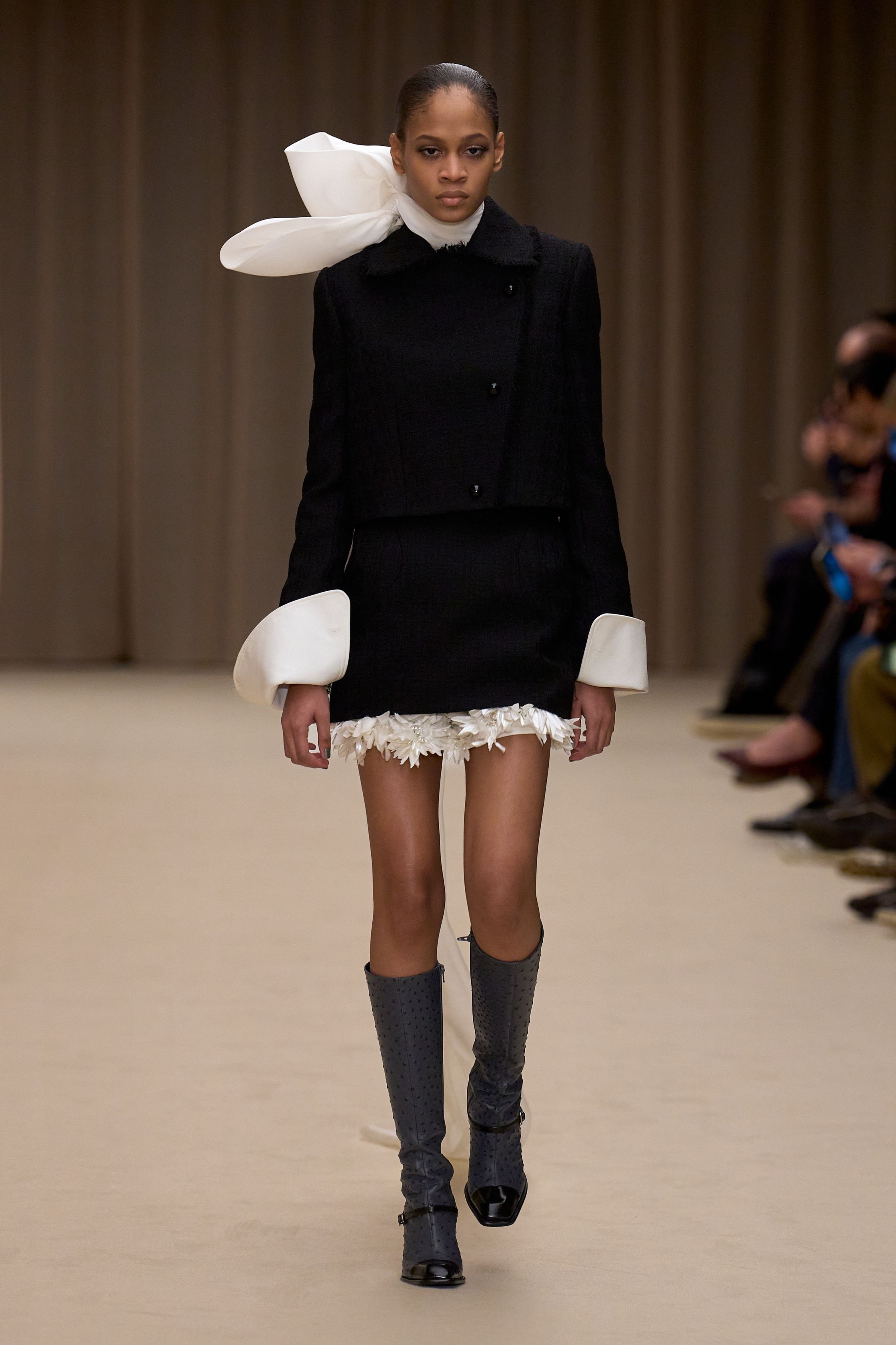 McQueen 本季延续品牌标志性的暗黑浪漫：收腰短裙套装、雕塑感肩线、精致刺绣礼服与戏剧化斗篷让整场秀充满哥特式戏剧张力。细腻蕾丝、金属光泽和建筑般轮廓塑造出强烈女性力量，同时保留麦昆一贯的浪漫与神秘-顽石频道趋势研究